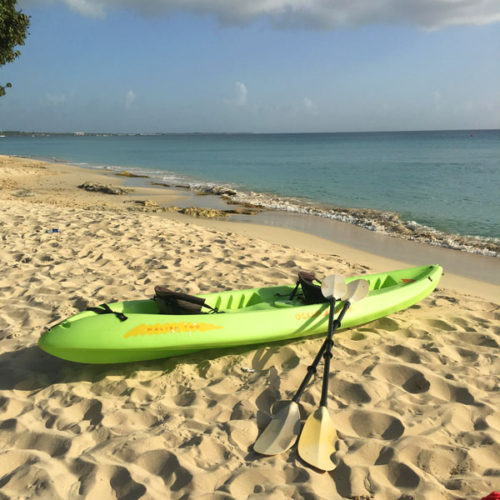 A kayak is sitting on the beach near the ocean.