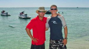 Two men standing next to each other on the beach.