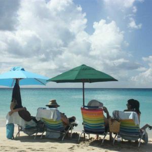 A group of people sitting on lawn chairs under umbrellas.