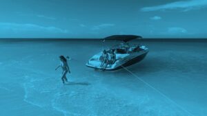 A person is standing in the water next to a boat.