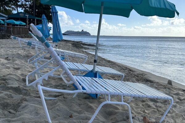 A beach with two lawn chairs and an umbrella.