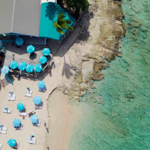 An aerial view of a beach with umbrellas and chairs.